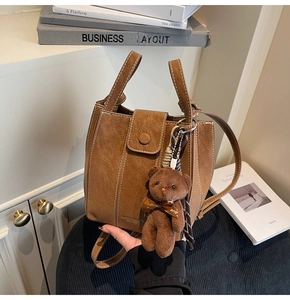 Brown lychee texture bucket bag with contrast stitching and plush bear charm