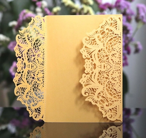 Macro detail of laser-cut wedding invitation cover with gold floral hollow patterns