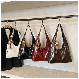Side view of large tote bags with metal studs, bear charms and woven tassels hanging