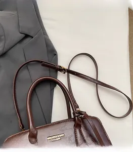 Detail view of dark brown vintage handbag with adjustable shoulder strap and top handles