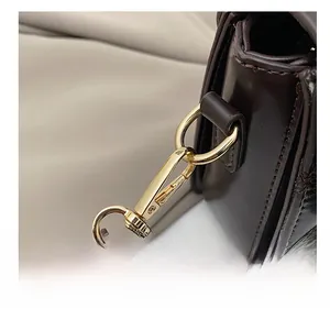 Detailed macro of golden metal hook and quilted stitching on dark brown leather bag