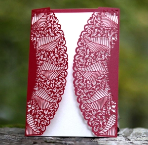 Elegant red laser-cut wedding invitation card with intricate lace leaf patterns and white insert