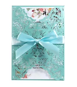 Detail of laser-cut tiffany blue wedding invitation with silk bow and floral insert