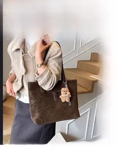 Detail of a large vintage brown suede tote bag with a cute bear pendant for daily commute