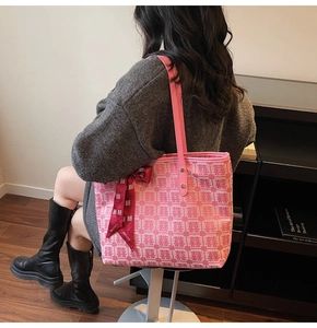 Detailed view of pink tote bag with woven Chinese characters and a red ribbon bow