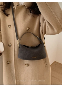 Close-up of dark grey leather crescent bag with golden clasp and vintage grain detail