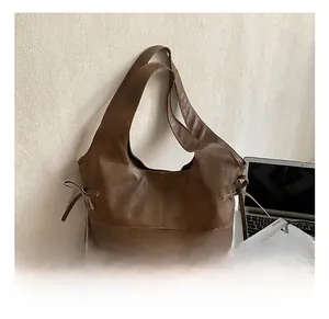 Detail of dark brown leather tote bag showing side bow tie and soft textured finish