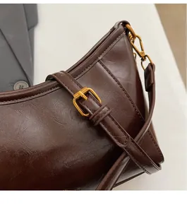 Dettaglio borsa sottobraccio retrò marrone scuro in pelle lucida con hardware dorato