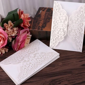 Elegant white laser-cut lace wedding invitations set on a vintage wooden background