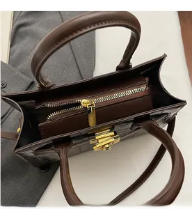 Detail view of brown crocodile texture handbag with gold hardware and zipper