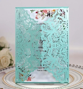 Detail of laser-cut glitter teal wedding invitation with delicate floral inner card