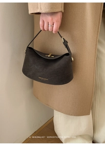 Close-up of minimalist dark brown leather handbag with metal turn-lock and retro design