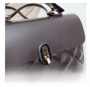 Detail of dark brown handbag with quilted stitching and premium black gold oval metal lock