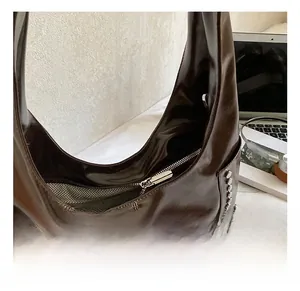 Close-up of silver metal rivets and polished leather on a dark brown shoulder bag