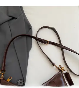 Dettaglio della tracolla lunga regolabile con fibbia dorata su borsa in pelle marrone scuro