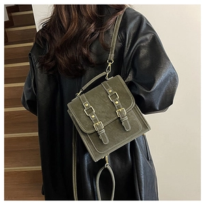 Detail of vintage olive green backpack with double strap metal buckles on dark wood stairs