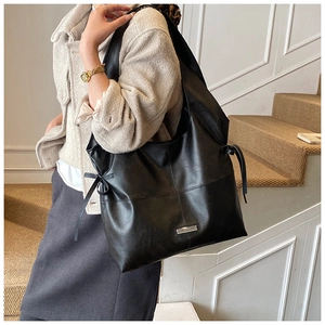 Detail of vintage black oil wax tote bag with side drawstring bow and cross stitching