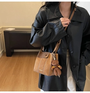 Detail of vintage brown bucket bag featuring contrast stitching and cute teddy bear charm