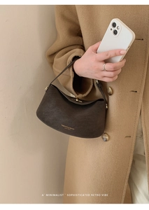 Detail of dark brown matte leather bucket bag with gold foil lettering and top handle