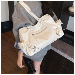 Detail of a large cream-colored motorcycle-style tote bag with silver metal buckles