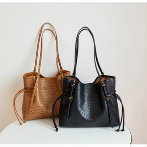 Detail view of black and brown ostrich leather tote bags with elegant drawstring accents