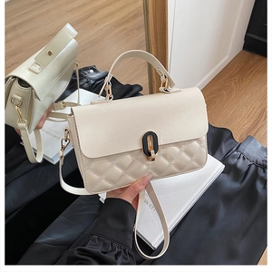 Detailed macro view of beige faux leather handbag featuring rhombus quilting and gold buckle
