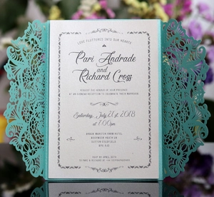 Detail of laser-cut floral invitation cover in teal with pearlescent inner card