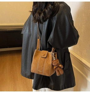 Detail of a brown vintage bucket bag with a cute plush bear charm on a model