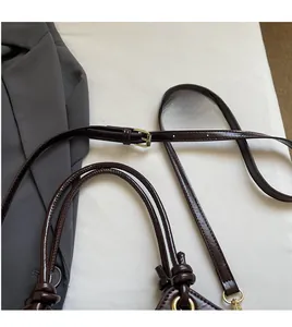 Detail of dark brown leather bucket bag with knotted handle and adjustable gold strap