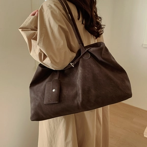 Detail view of large dark brown suede tote bag with slim straps and matching small pouch