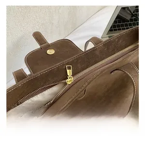 Detail showing the brown suede texture, golden hardware, and herringbone fabric lining