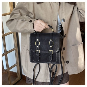 Detail of black vintage leather backpack featuring white stitching and gold buckles