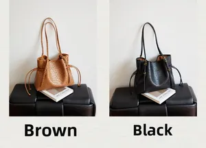 Detail view of brown and black ostrich pattern tote bags with gold hardware and side drawstrings
