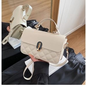 Detail of cream white handbag with quilted pattern, gold twist lock and shoulder strap