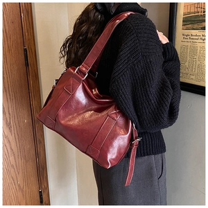 Detail view of dark red vintage tote bag with oil-wax texture on a female shoulder
