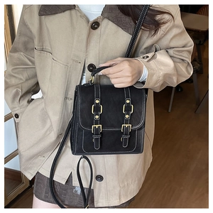 Detail view of a vintage black leather crossbody bag with white stitching and gold buckles