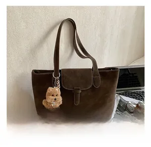 Detail of dark brown matte tote bag with contrast stitching and plush bear charm