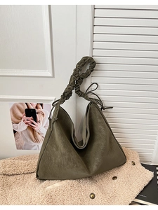 Detail of olive green slouchy tote bag featuring a textured pleated shoulder strap