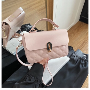 Detail of light pink quilted handbag featuring a black-gold oval lock on black silk