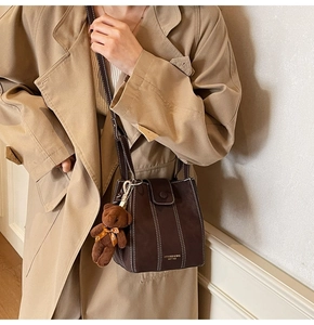 Detail of vintage brown bucket bag with contrast stitching and small bear pendant charm