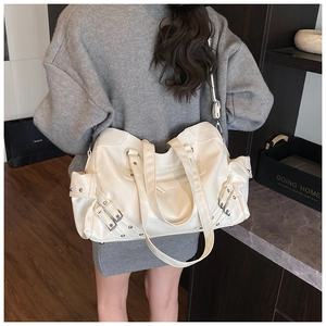 Detailed view of white oversized tote bag with metal buckles and rivets on sweater