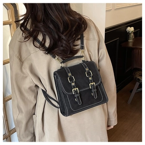 Detailed view of black vintage faux leather backpack with white stitching on beige coat