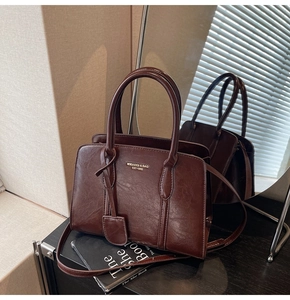 Detailed close-up of dark brown vintage faux leather shoulder bag with golden brand logo