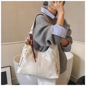 Vue détaillée du grand sac cabas crème avec rivets métalliques et breloque ours sur mannequin