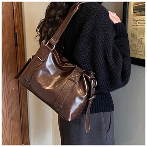 Detail of dark brown vintage faux leather tote with glossy texture and wide shoulder strap