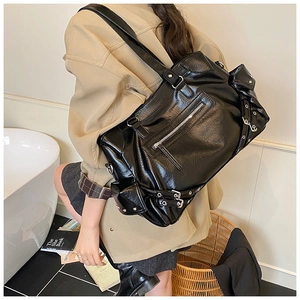 Detail of black glossy PU leather tote bag with silver zippers and moto style buckles