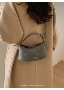 Detail of minimalist bucket bag in matte leather with gold logo and crossbody strap