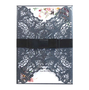 Detail of laser-cut wedding invitation with dark grey glitter cover and black silk bow