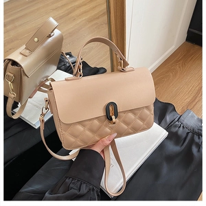 Detail of beige leather handbag with quilted texture and gold-tone metal twist lock