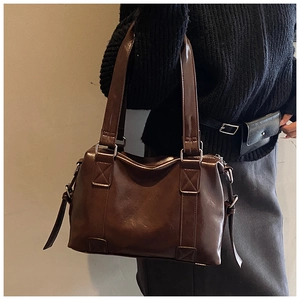 Detail view of deep brown glossy leather tote bag with silver adjustable buckles